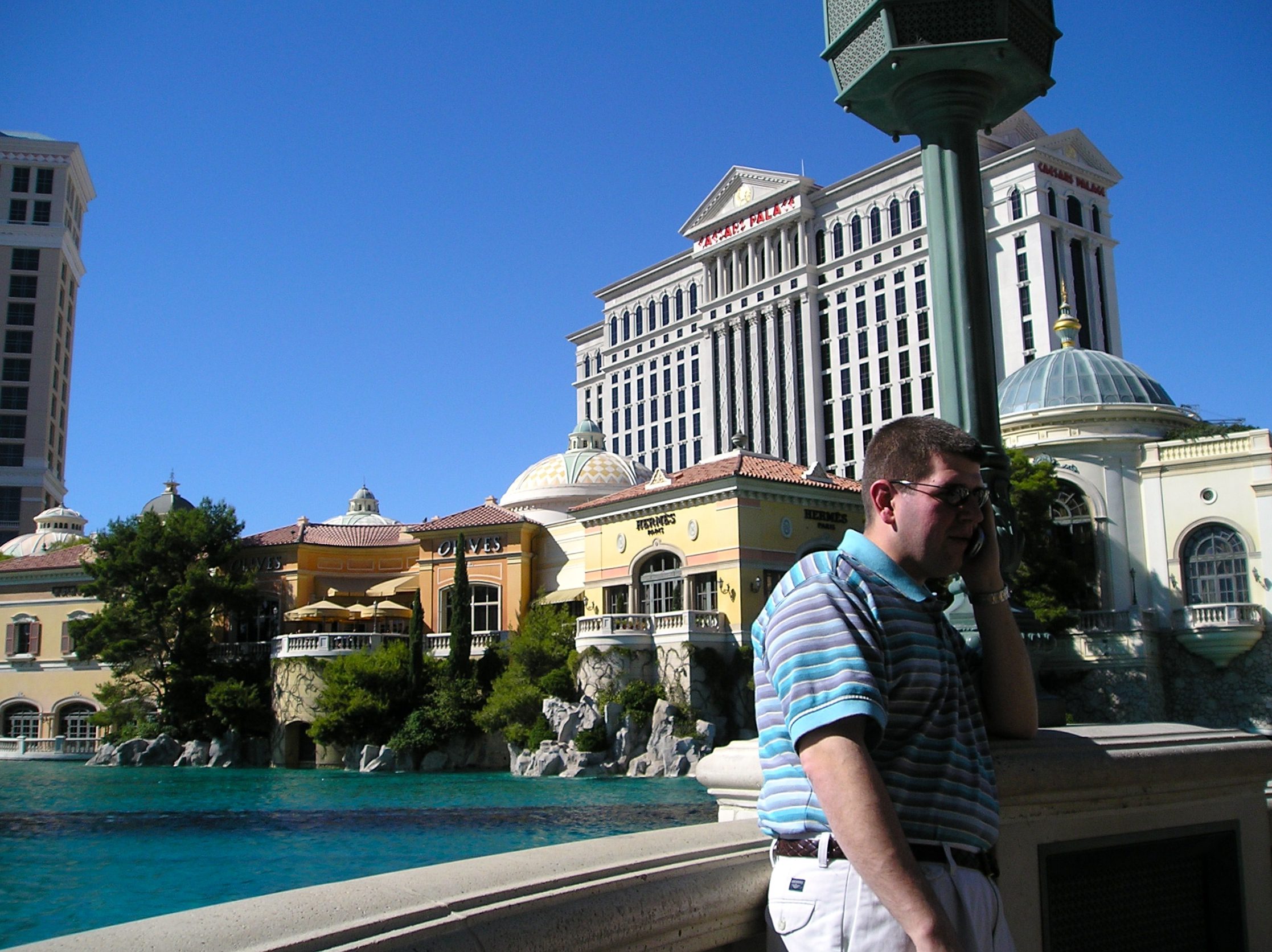 a man standing by a pool with buildings in the background
