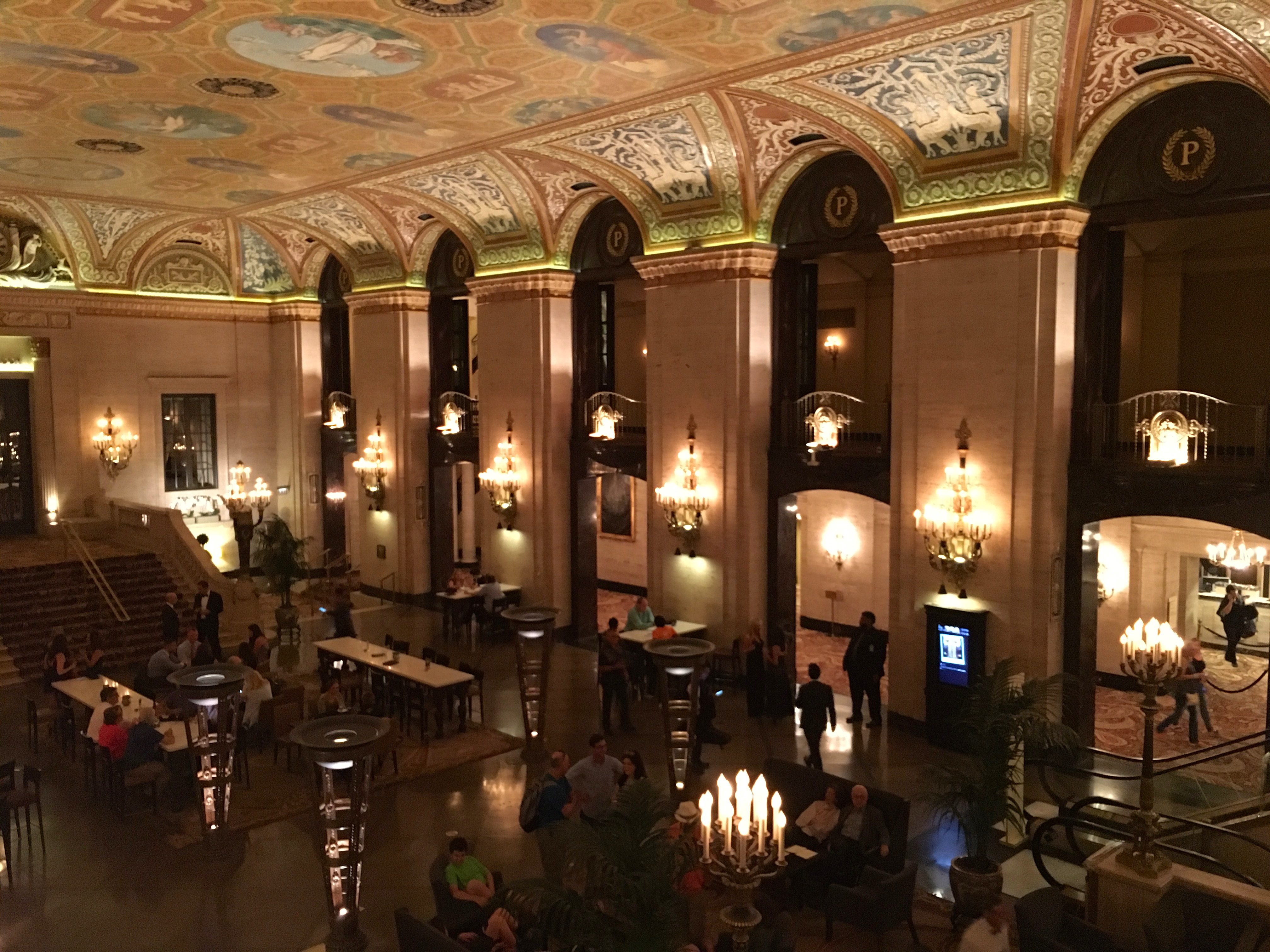 a large room with many people and chandeliers