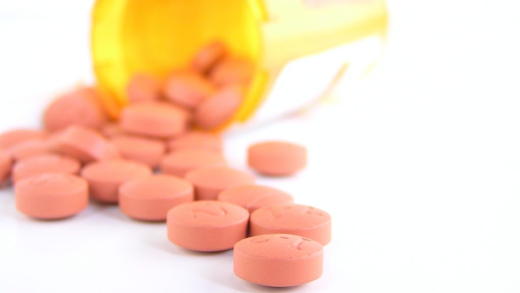 close-up of a pill bottle spilling out of pills