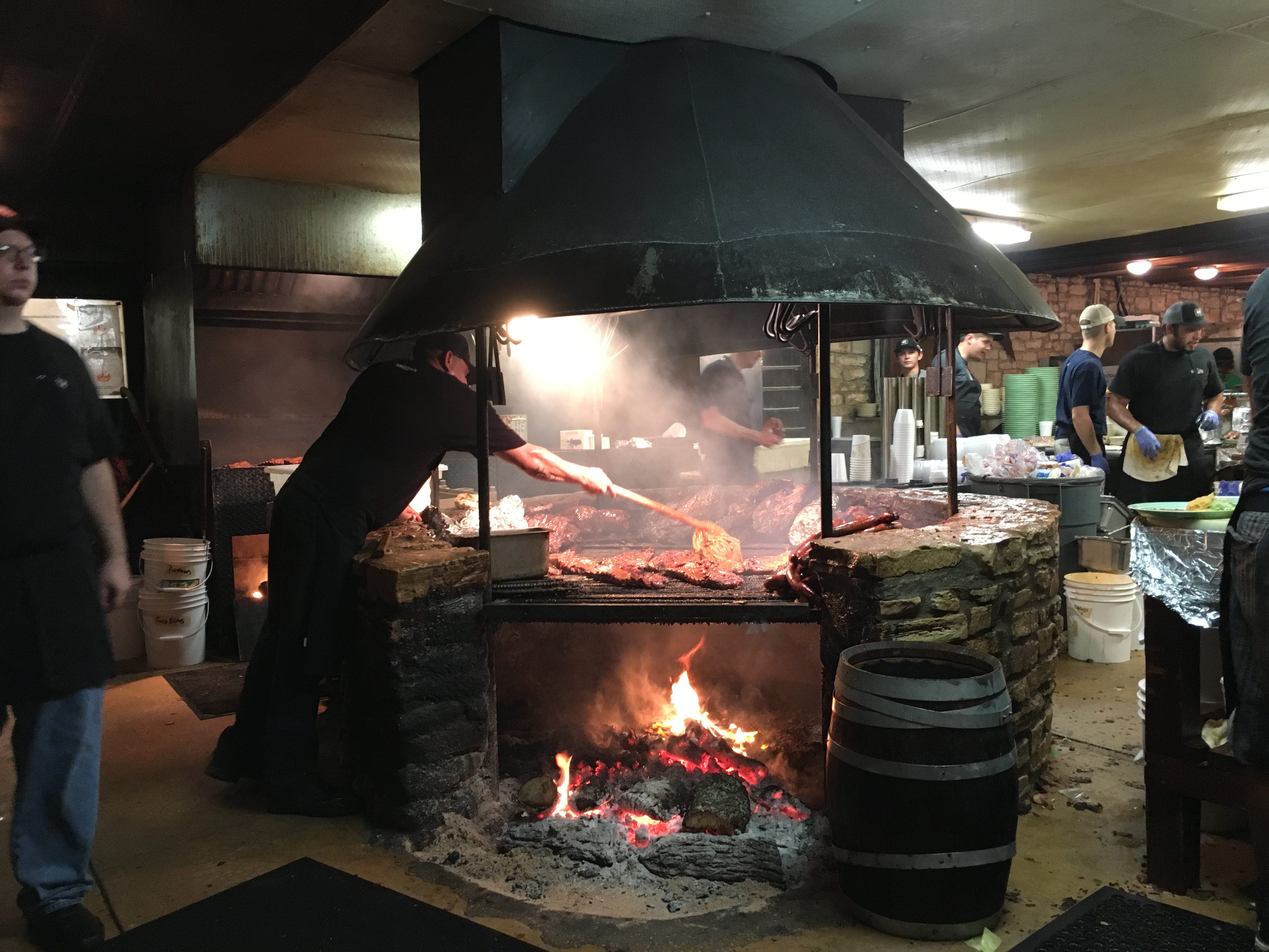 a man cooking meat in a large fireplace