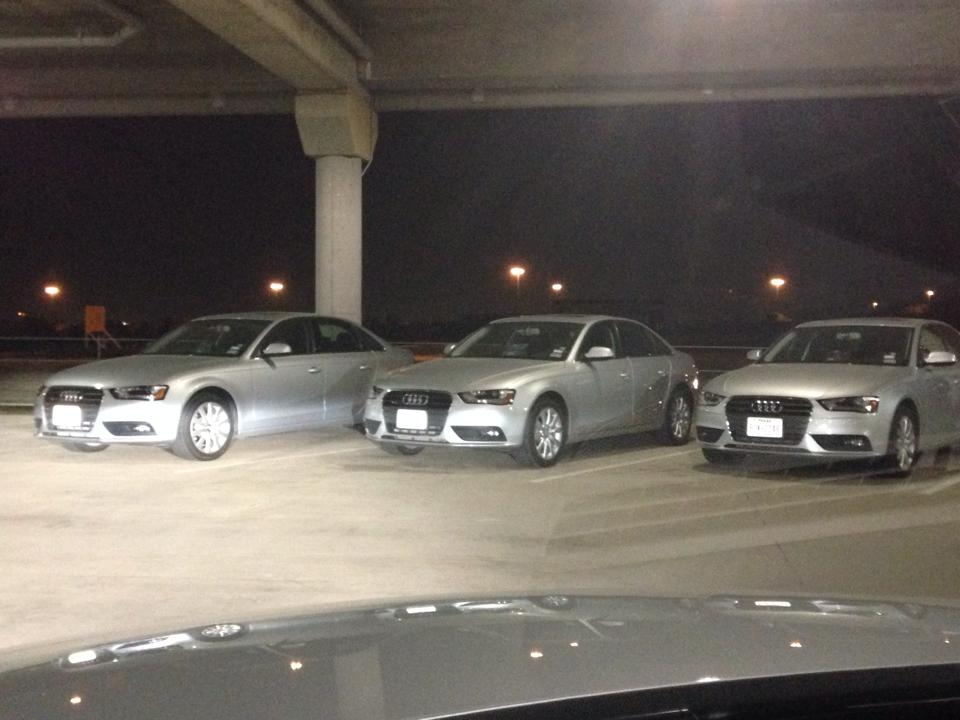 a group of silver cars parked in a parking lot