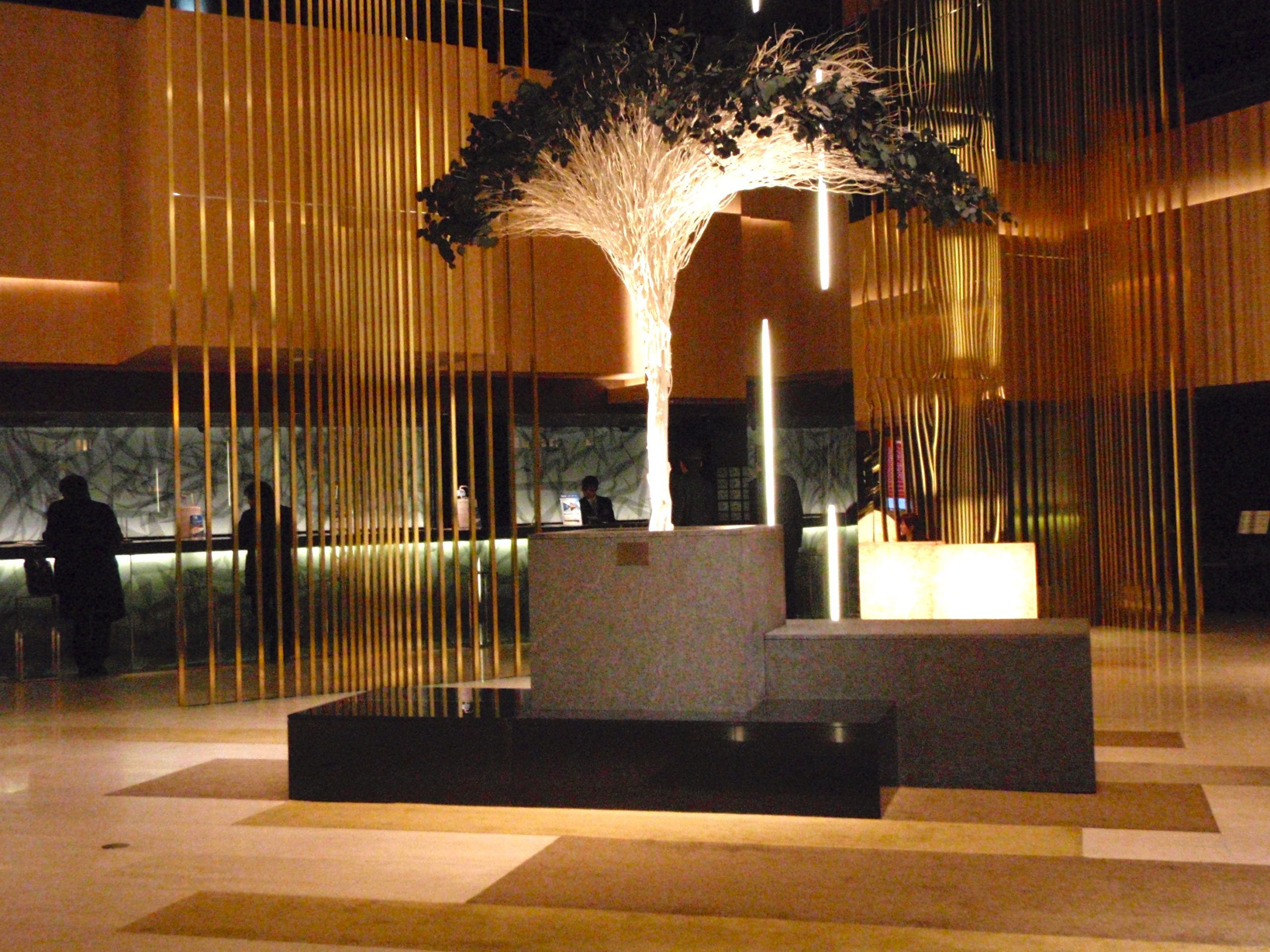 a lobby with a tree and gold walls