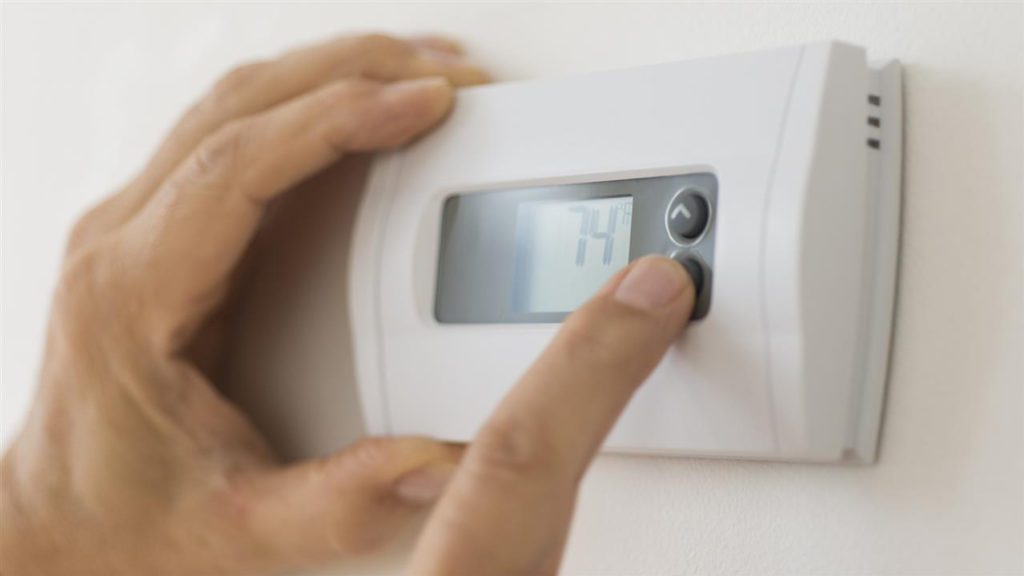 a person's hand pressing a thermostat