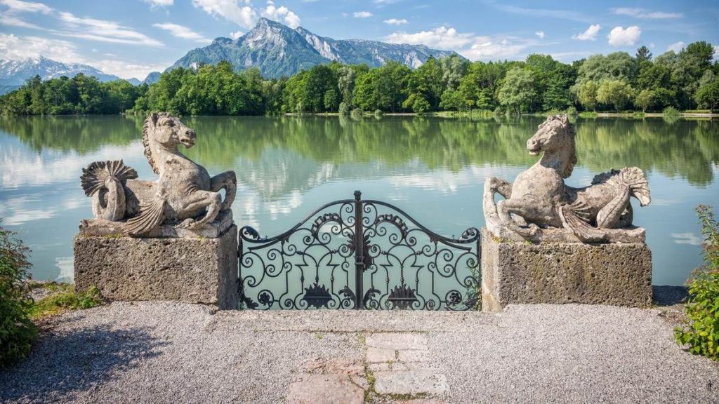 a stone gate with a lake and horses statues