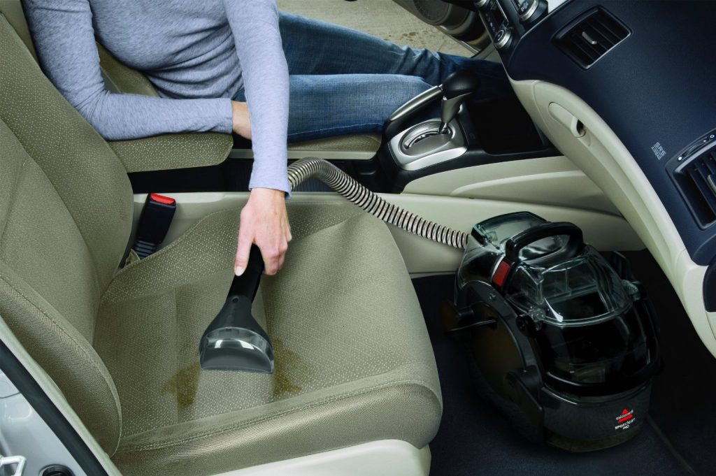 a person vacuuming the seat of a car