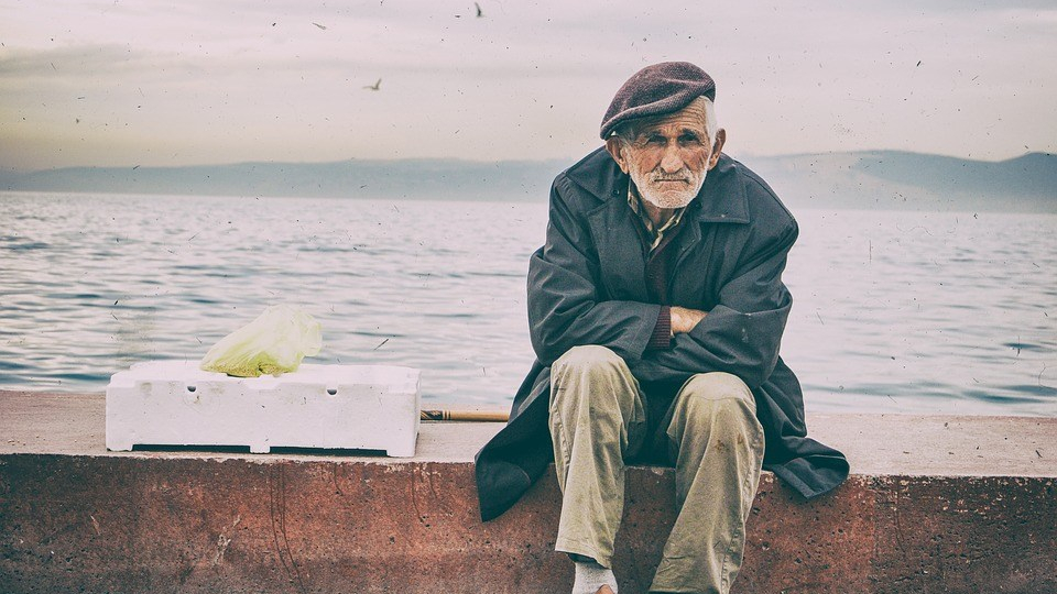 an old man sitting on a ledge near water