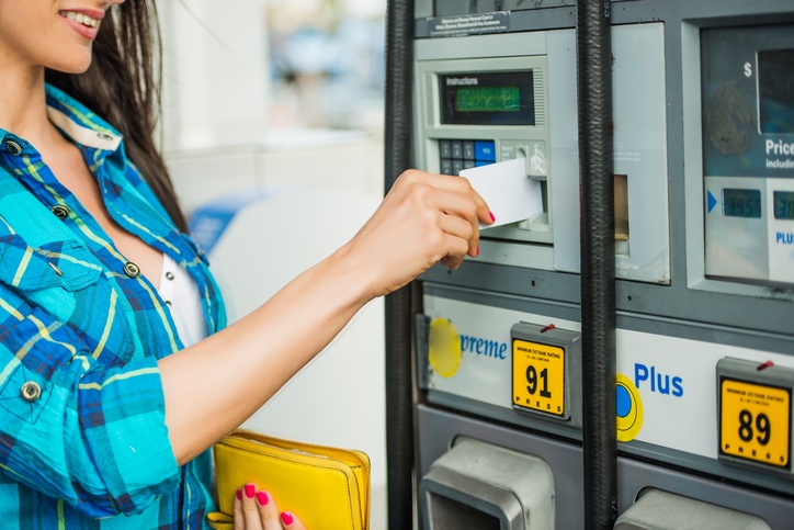 a woman using a card to pay at a gas pump