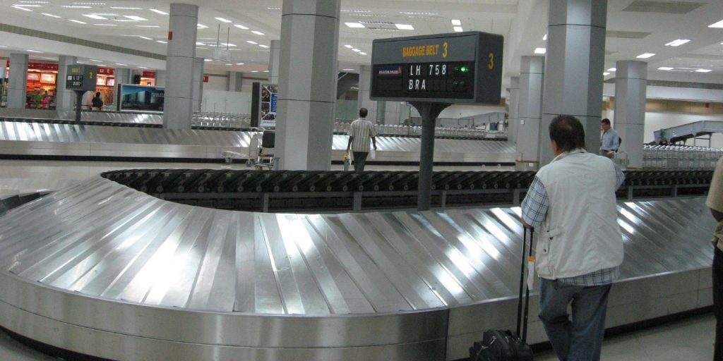 a man standing next to a baggage claim area