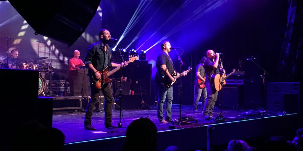 a group of men on a stage with guitars and microphones