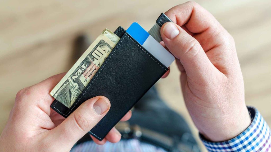 a person holding a wallet with money and credit cards