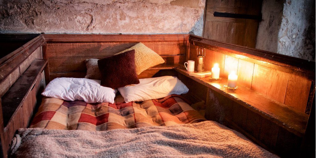 a bed with pillows and candles on a table