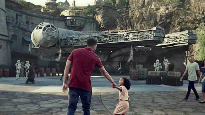 a man and child holding hands in front of a spaceship