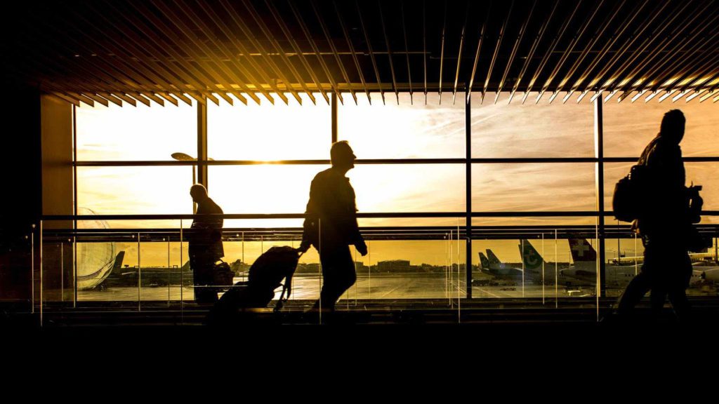 people walking in an airport with a window