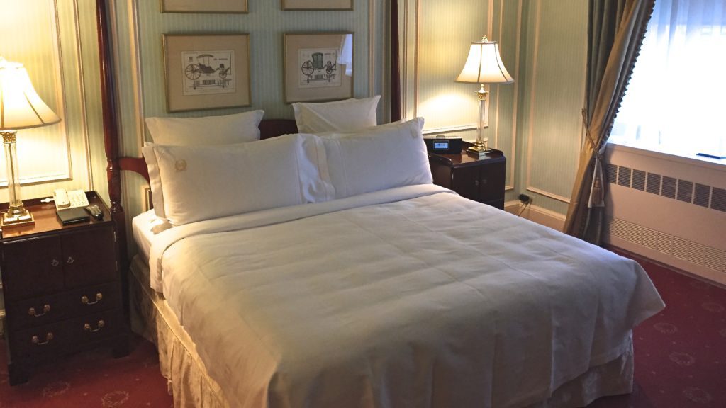 a bed with white sheets and lamps