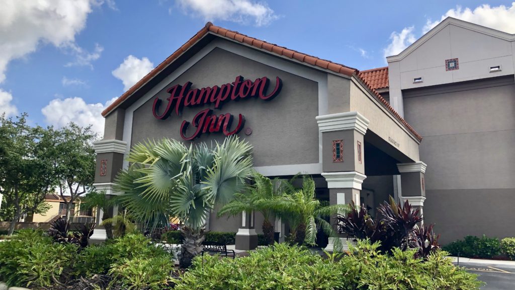 a building with palm trees and a sign