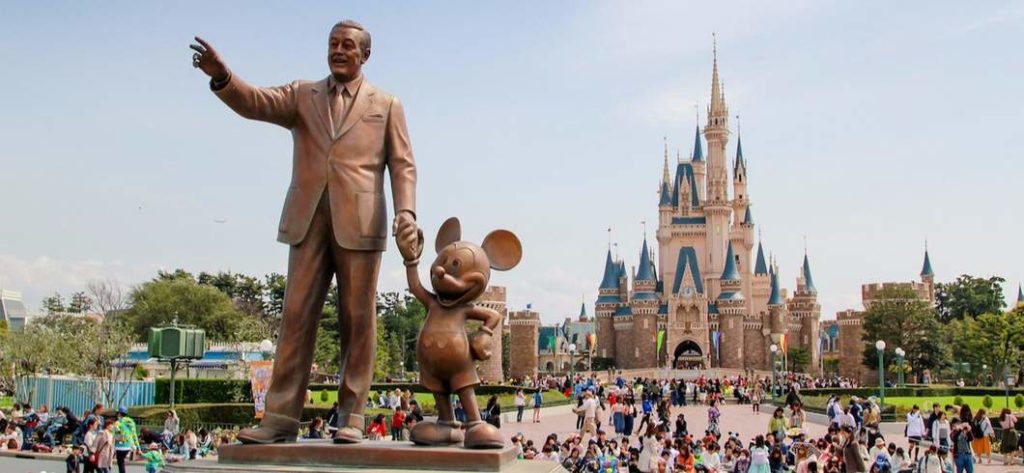 a statue of a man holding a mouse and a crowd of people