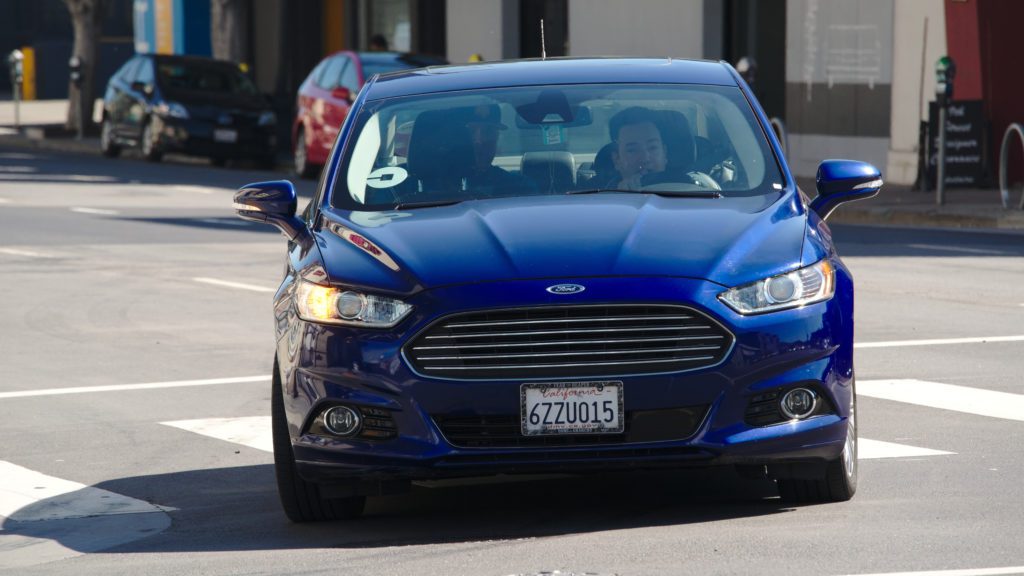 a couple of people driving a blue car