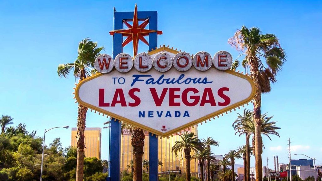 a sign with palm trees and blue sky with Welcome to Fabulous Las Vegas sign in the background