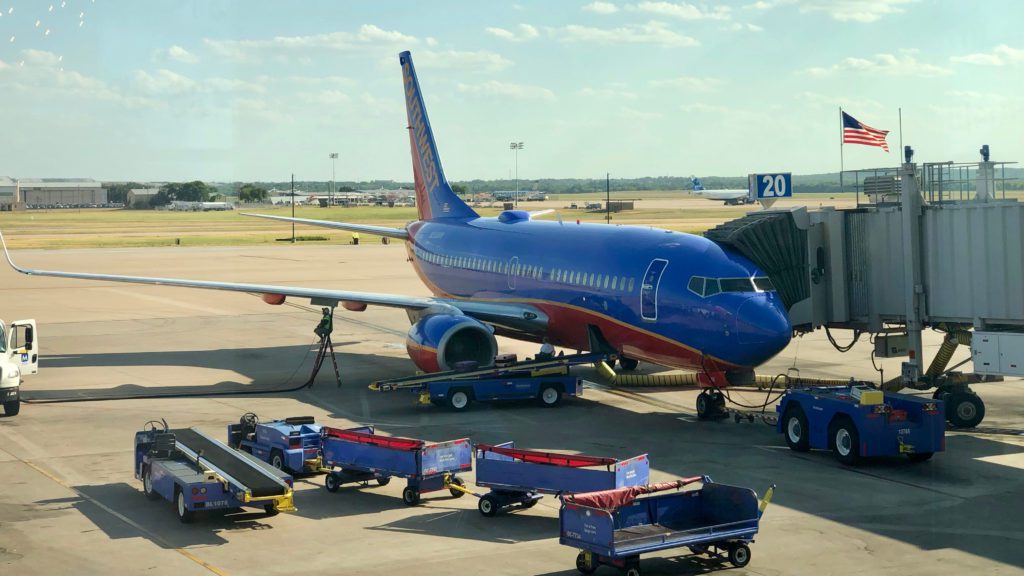 a blue airplane with red stripes on the side and a blue trailer on the side