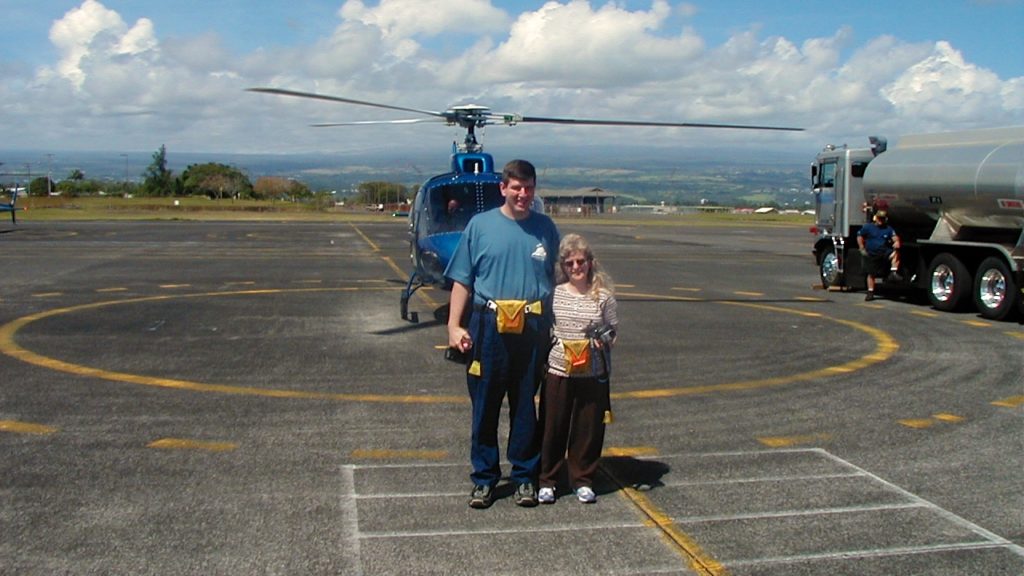a man and woman standing in front of a helicopter