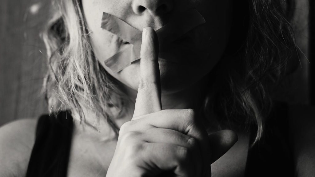 a woman with tape over her mouth and finger on her mouth