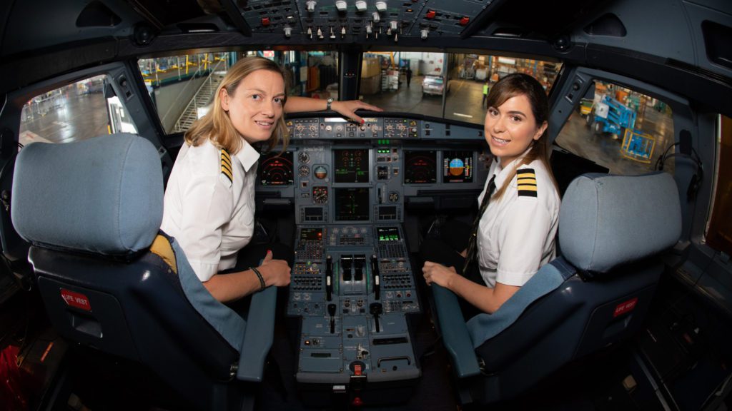 two women in uniform sitting in a cockpit