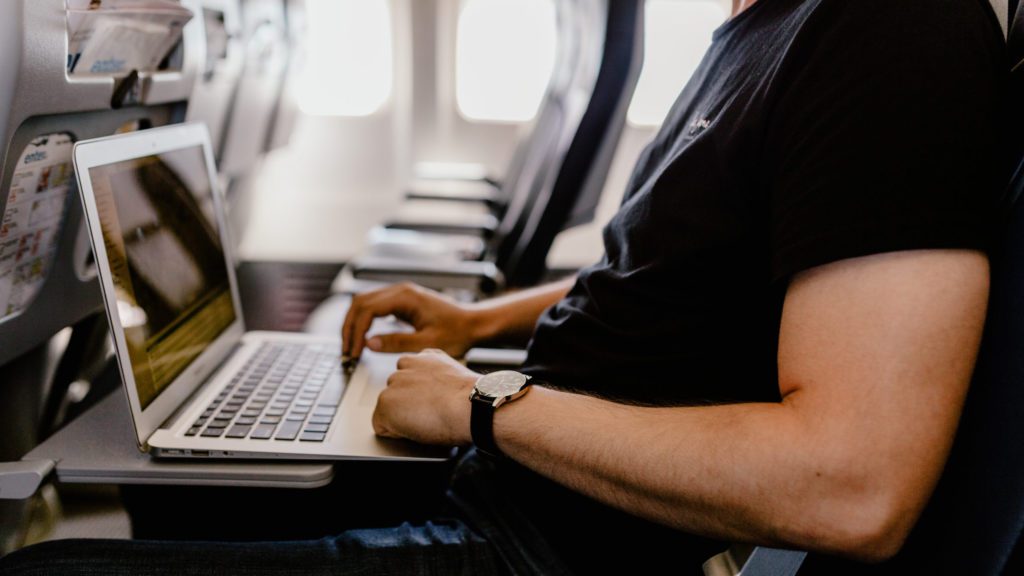 a man sitting in an airplane using a laptop