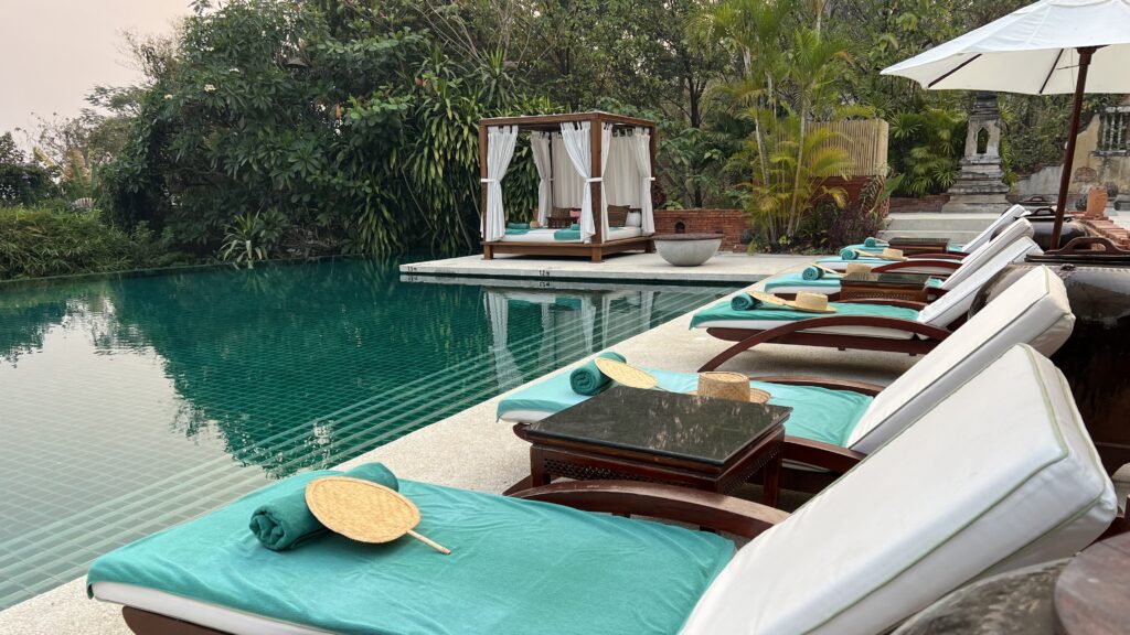 a pool with lounge chairs and a bed