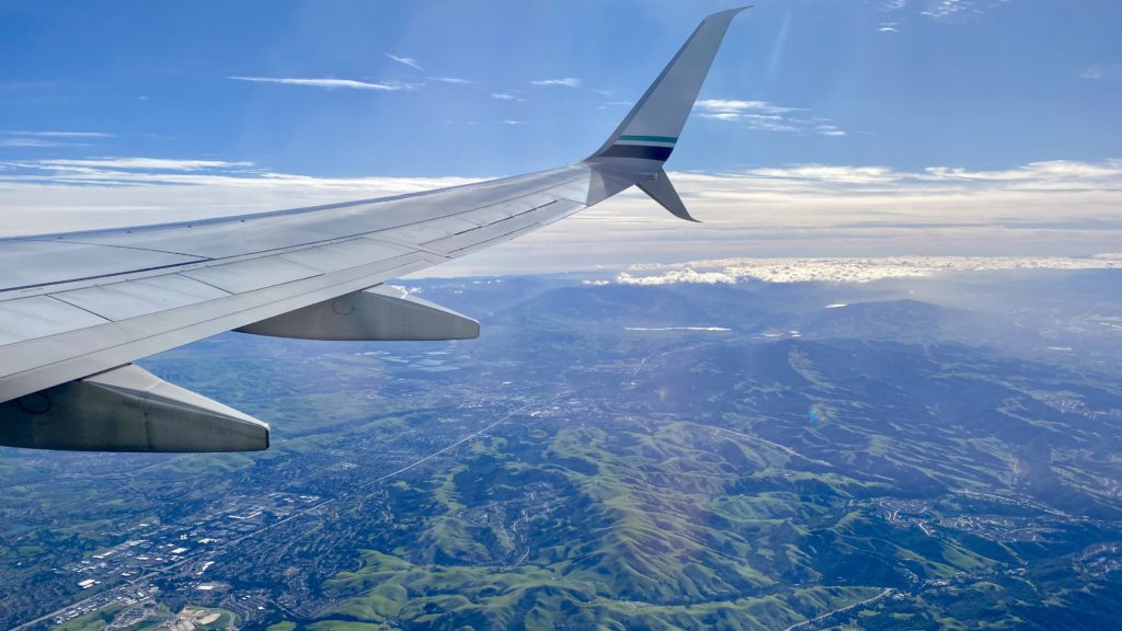 an airplane wing and view of a city and mountains