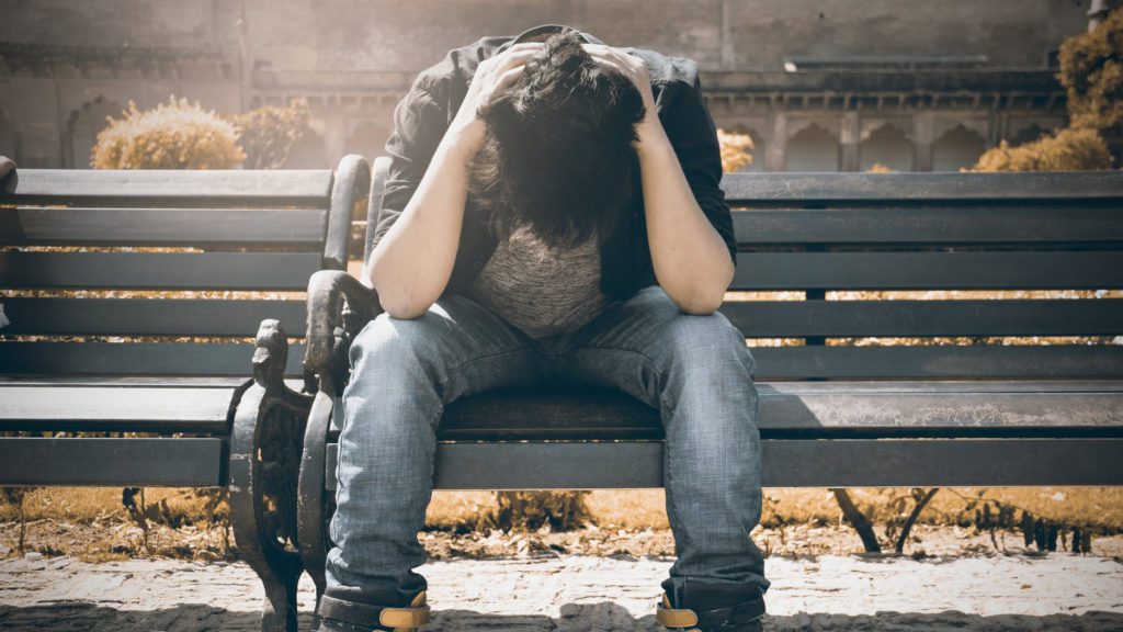 a man sitting on a bench with his head in his hands