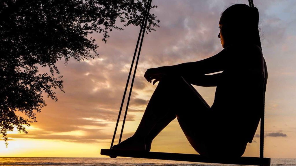 a silhouette of a woman sitting on a swing