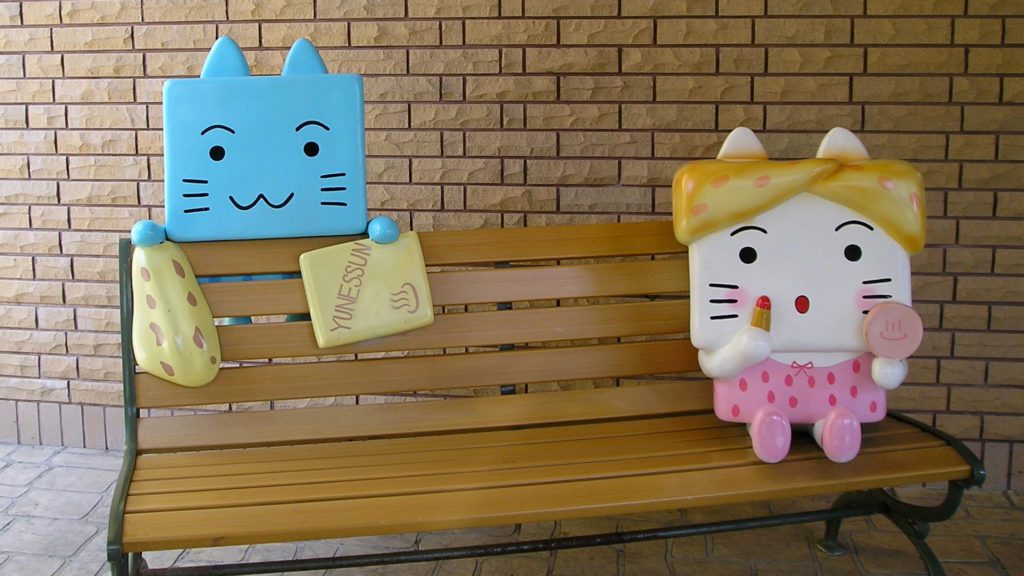 a bench with a couple of cat figurines