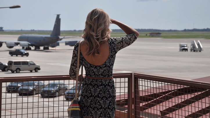 a woman in a dress looking at an airplane