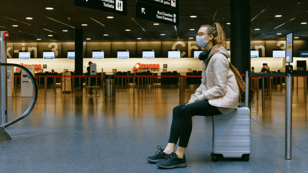 a woman sitting on a luggage in an airport