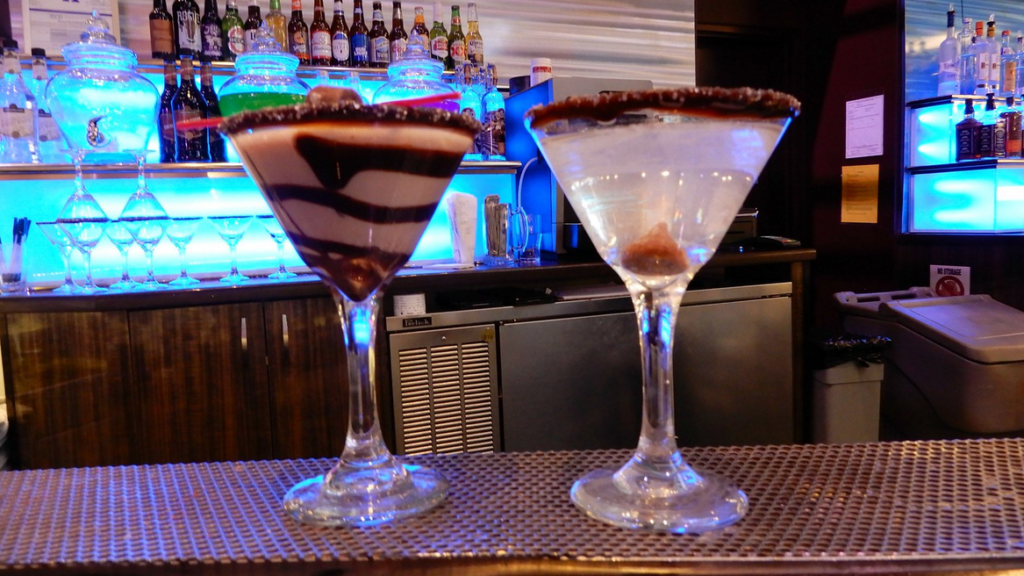 two glasses of drinks on a bar