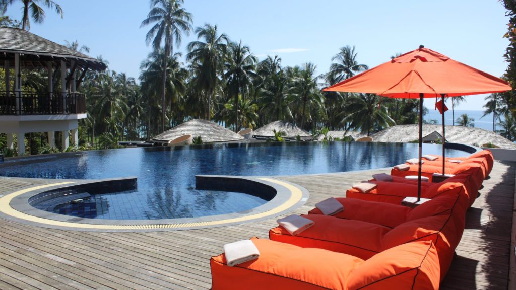 a pool with orange chairs and umbrellas