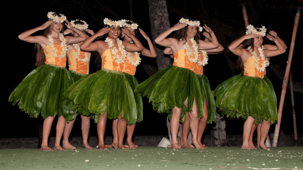 a group of women wearing green and orange dresses and flowers around their heads