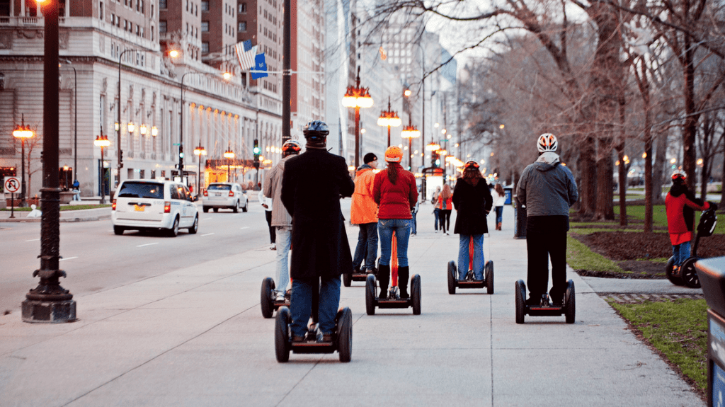 a group of people riding segways on a city street