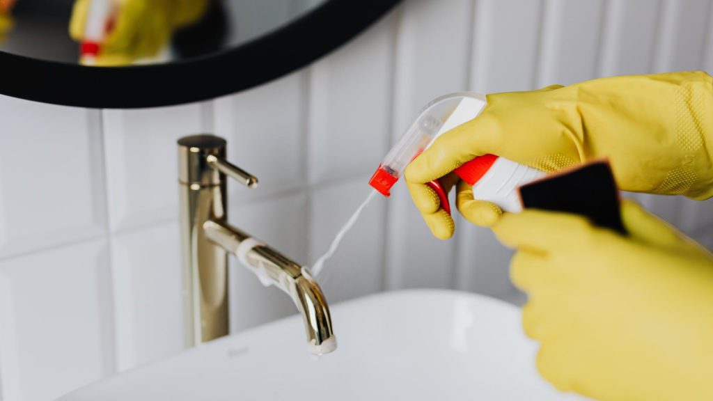 a person spraying a cleaning product into a faucet