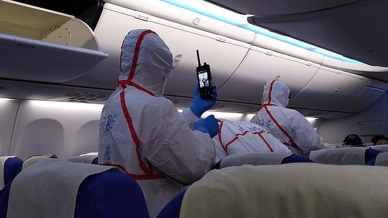 people in protective gear on an airplane