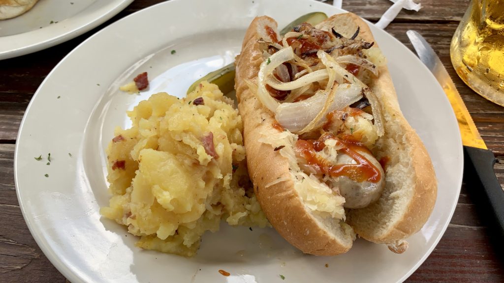 a hot dog with onions and potatoes on a plate