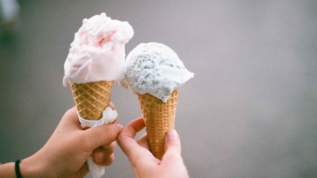 two hands holding ice cream cones