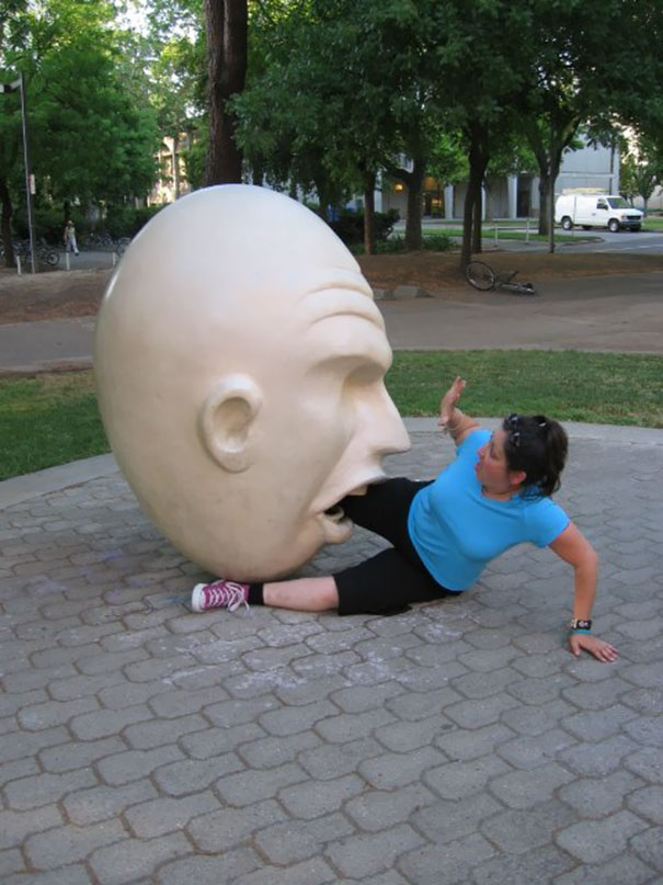 a woman biting a large sculpture of a head