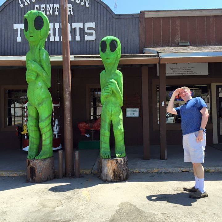 a man standing in front of two green alien statues
