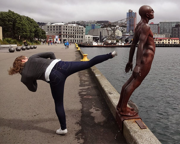 a woman stretching her leg to a statue of a man