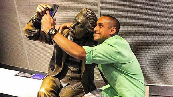 a man taking a selfie with a statue