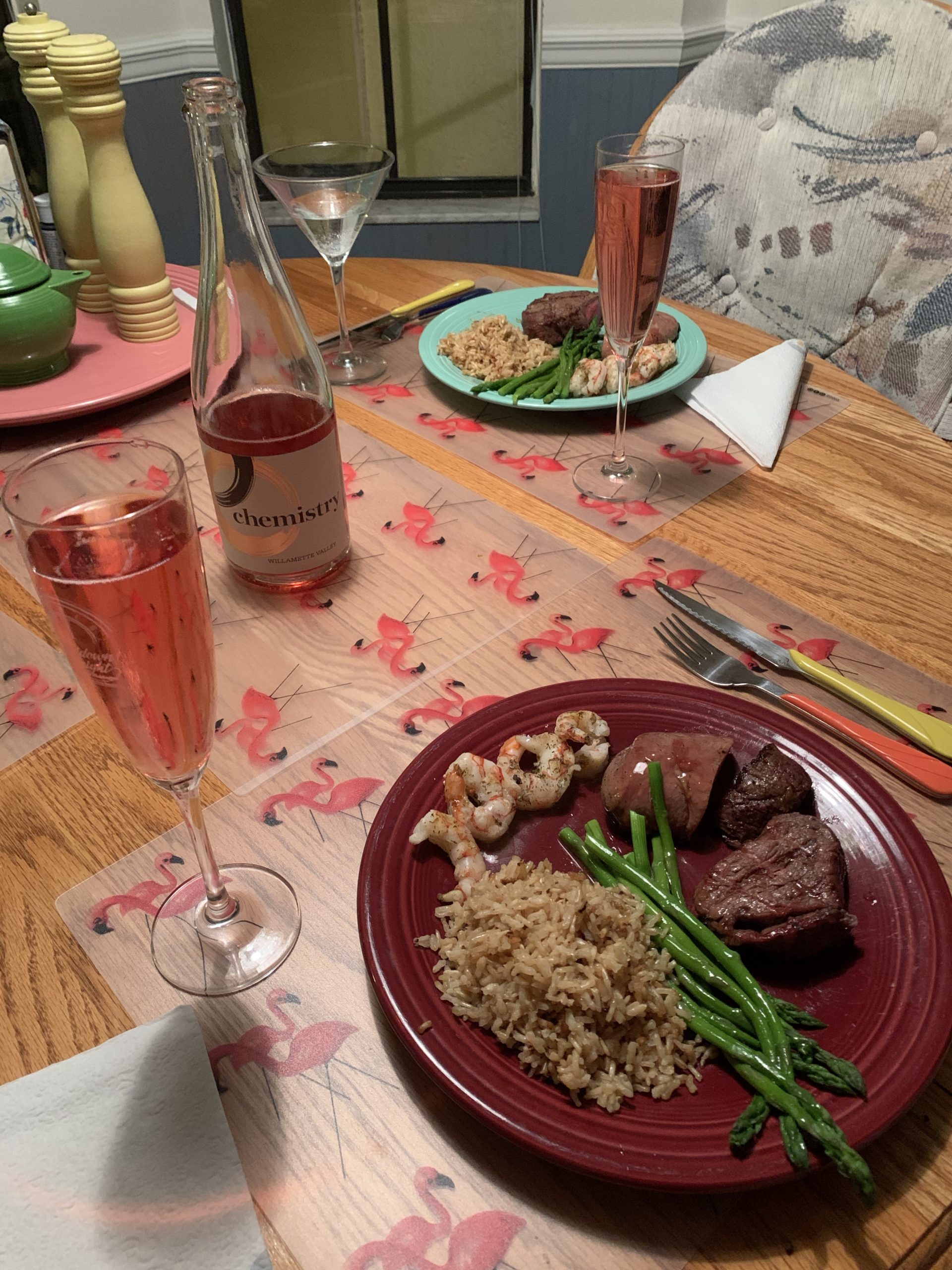 a plate of food on a table with wine glasses and a bottle of wine