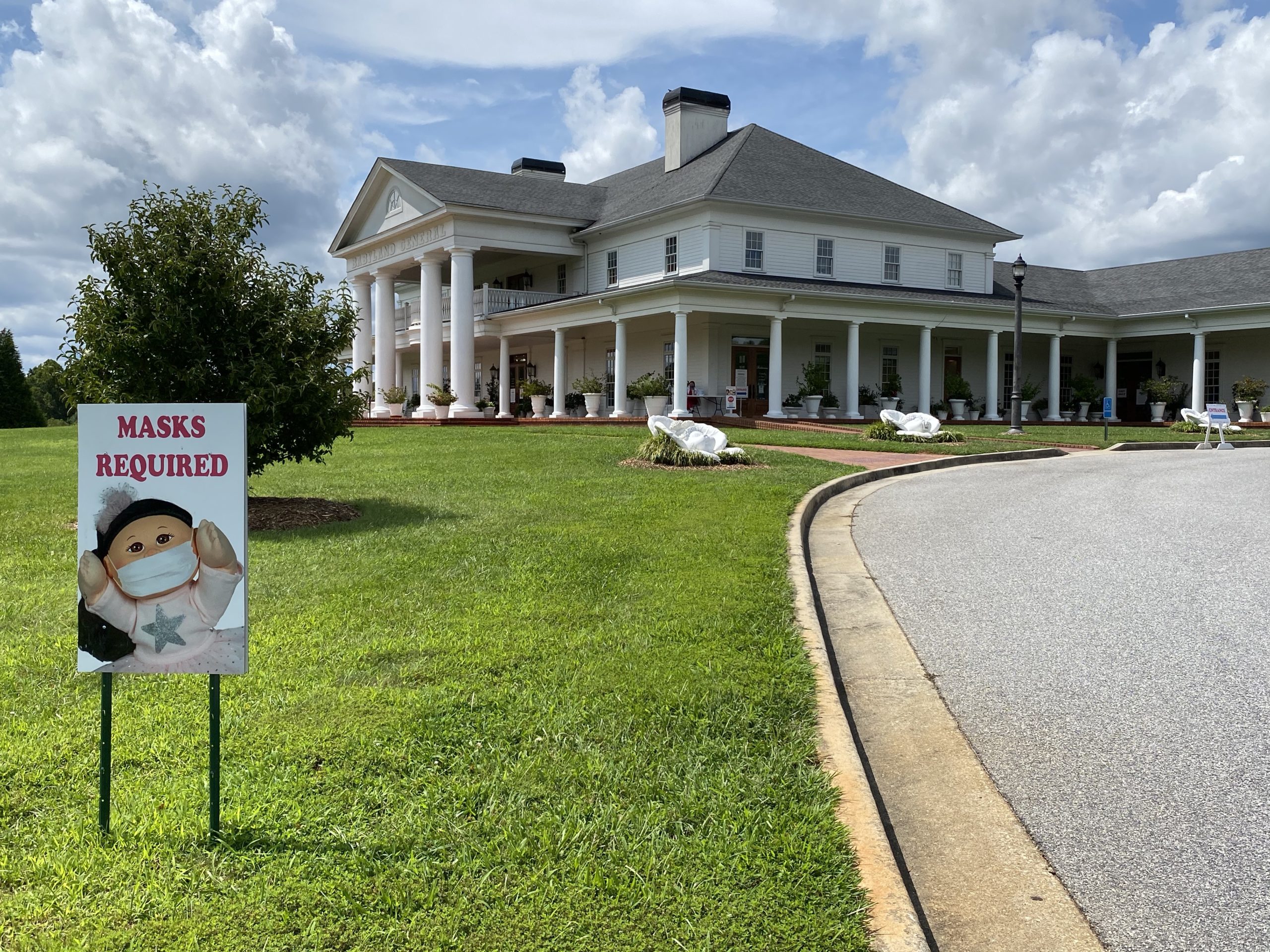 a sign in front of a large white house