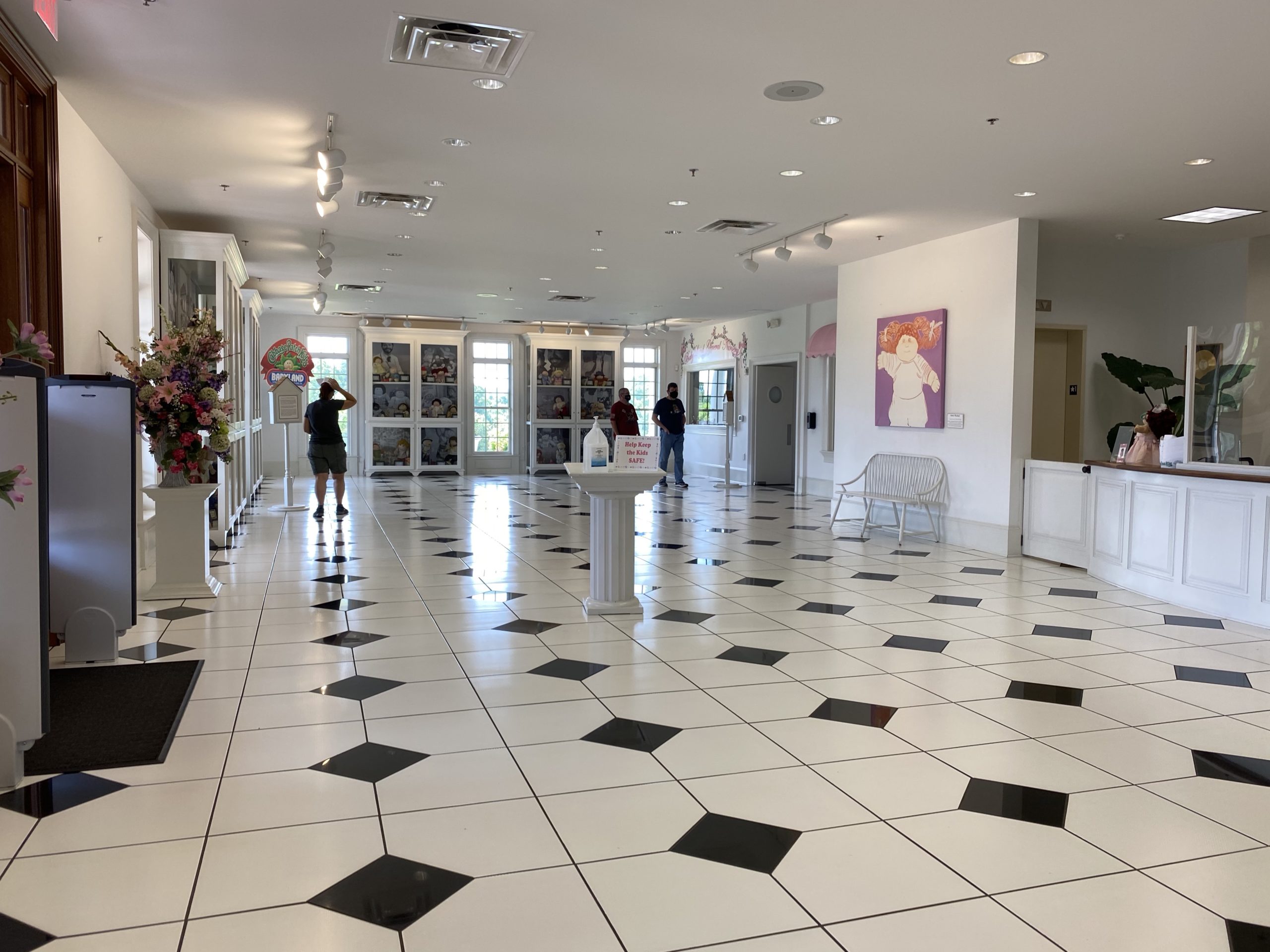 a room with black and white checkered flooring and people walking