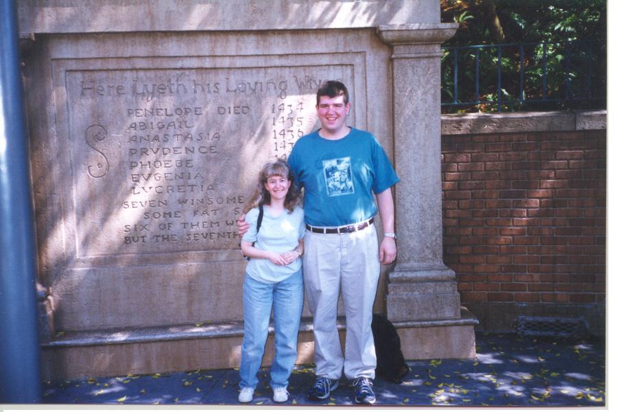 a man and woman standing in front of a stone wall